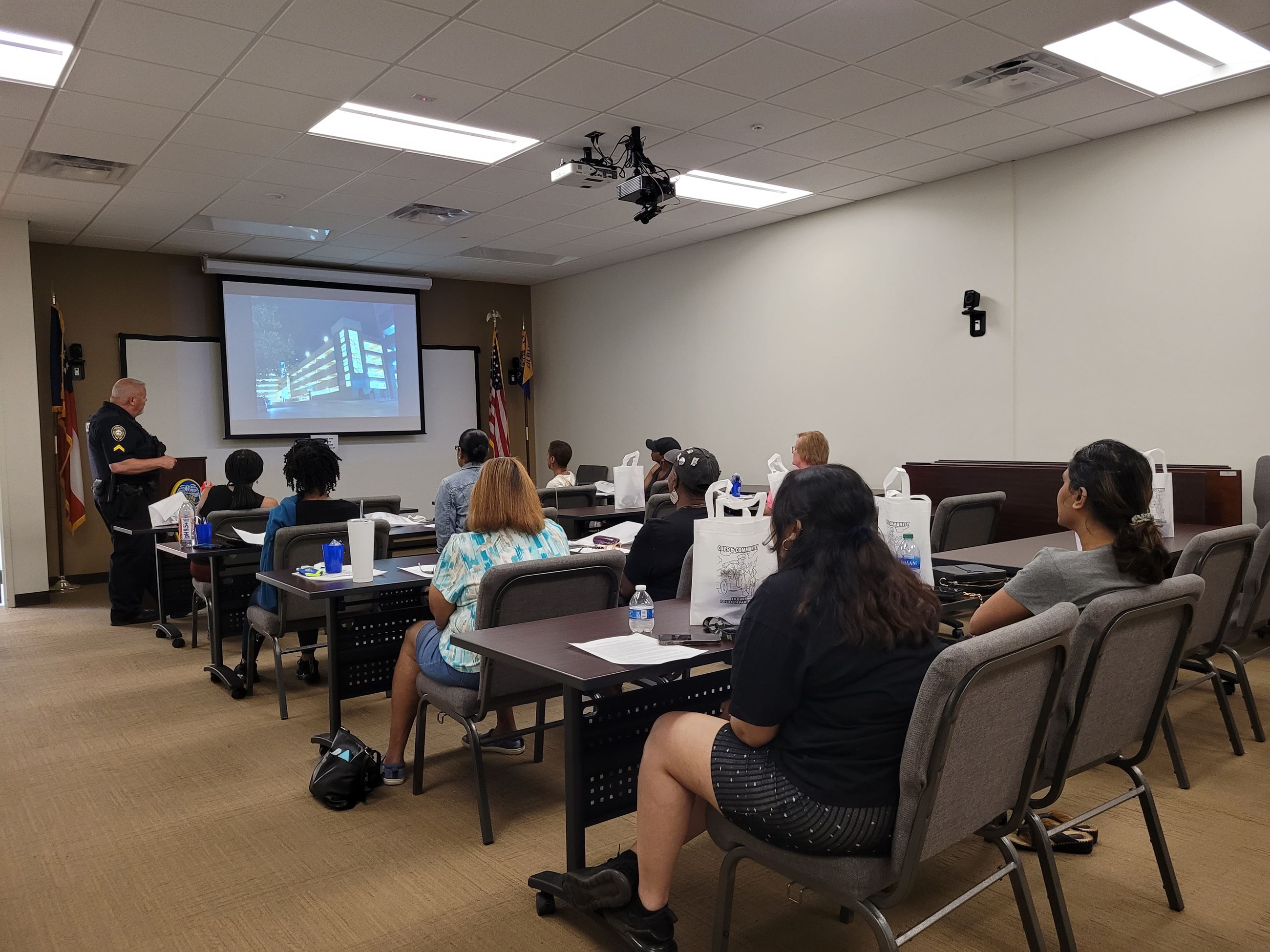 people sit in a classroom with police officer at front giving a presentation