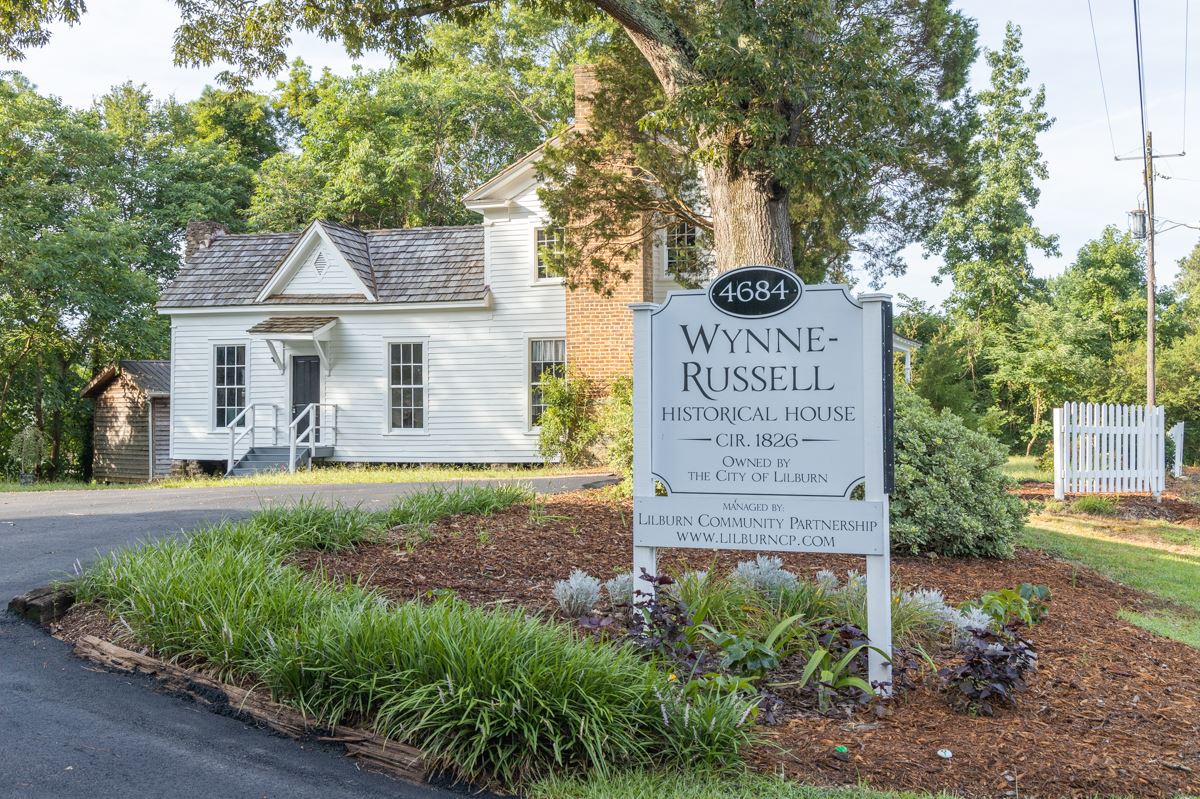 Historic White house with porch and sign that says Wynne Russell House