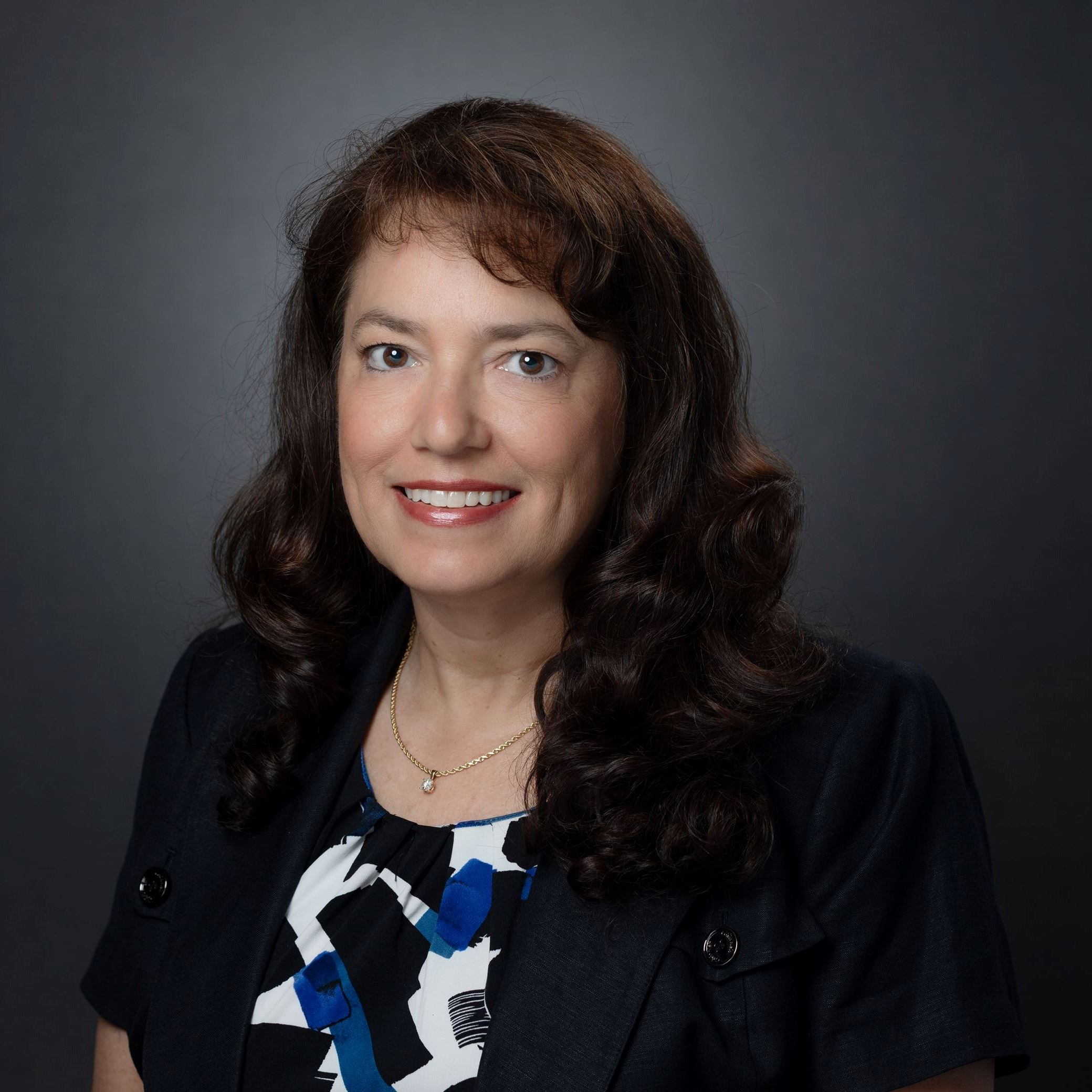 Headshots of Joellen Wilson female with long curly hair and bangs wearing a short sleeve suit