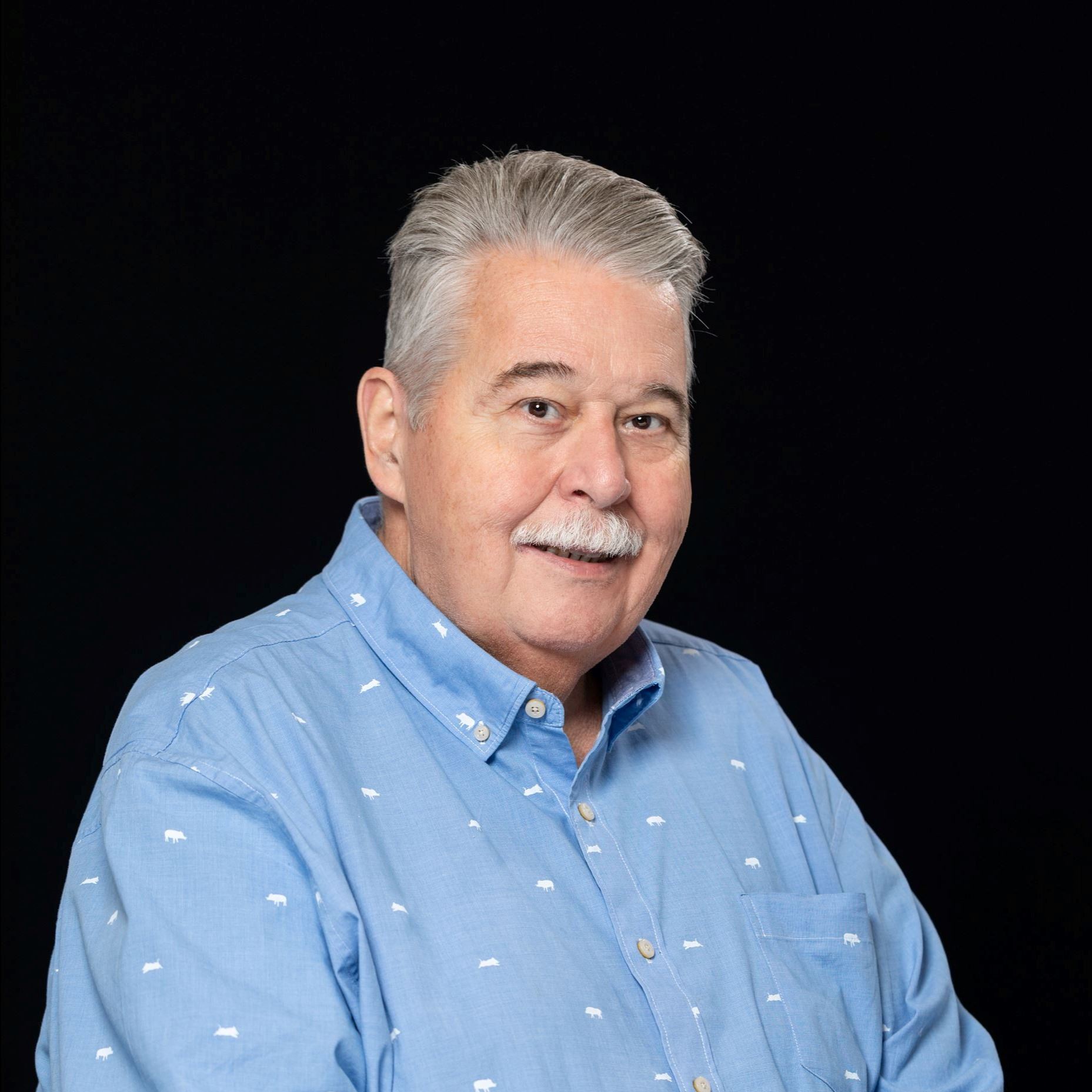 Headshot of Keith Cox male with gray hair and mustache wearing a light blue collared shirt