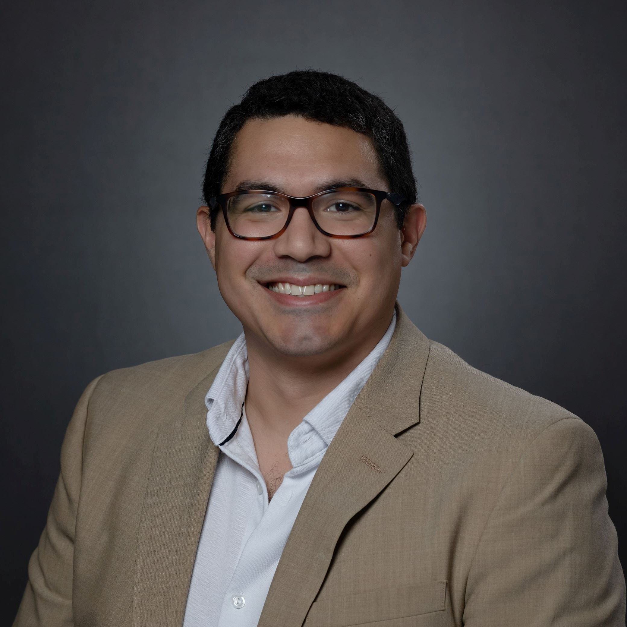 Headshots of Matt Ferreira male with short dark hair and glasses wearing khaki blazer